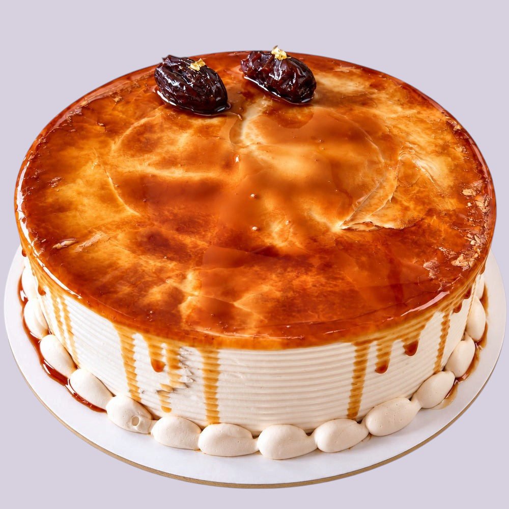Rhukra Cake House Sharjah date cake with caramel glaze and whole dates on top, served on a white cake board.