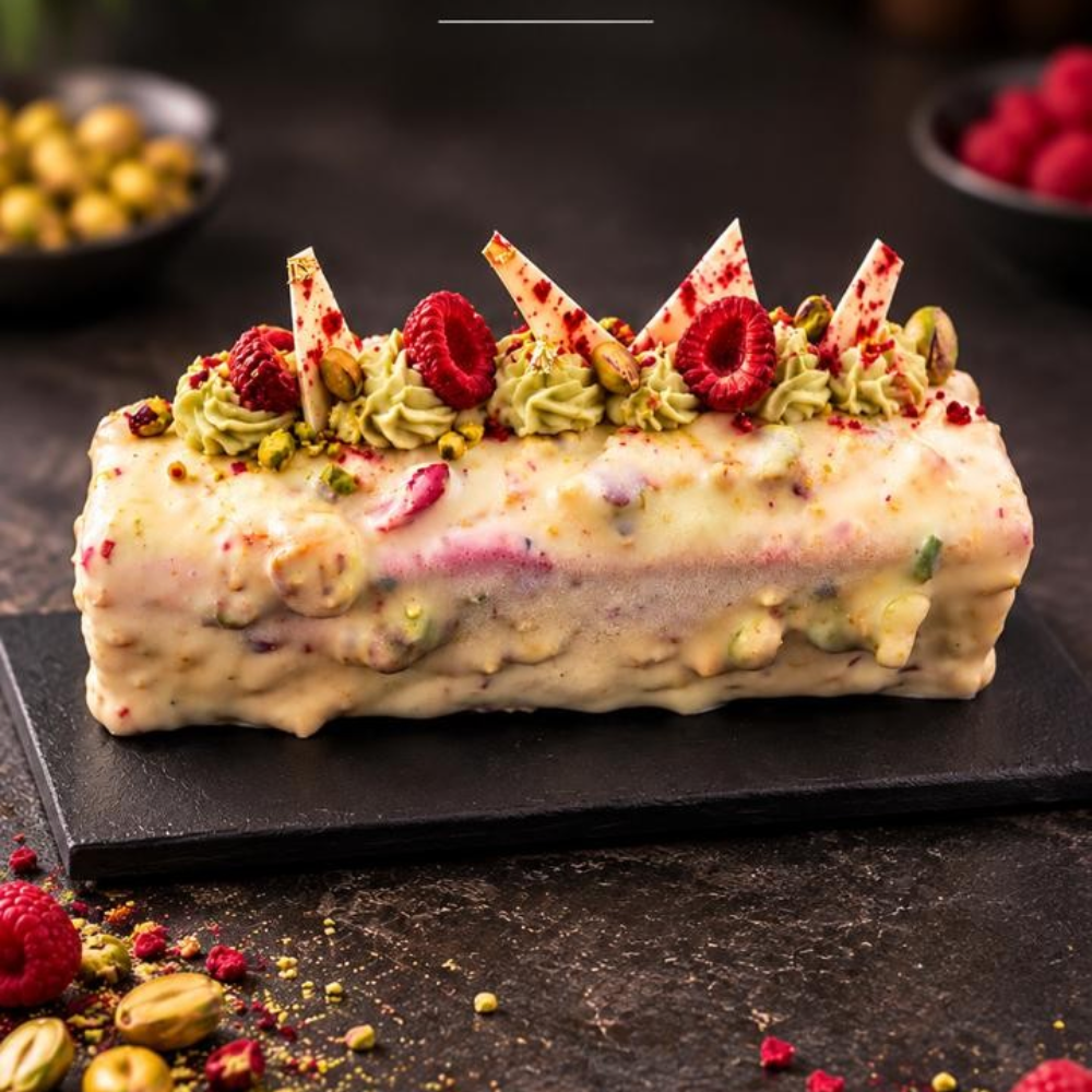 Rhukra Cake House Pistachio Red Cloud cake topped with fresh raspberries, pistachio cream, and white chocolate shards.