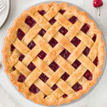 Rhukra Cake House almond tart with a golden lattice crust and visible red cherry fruit filling on a white surface.