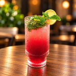 Rhukra Cake House cranberry mojito cooler in a ribbed glass with fresh mint and a lime slice on a wooden table