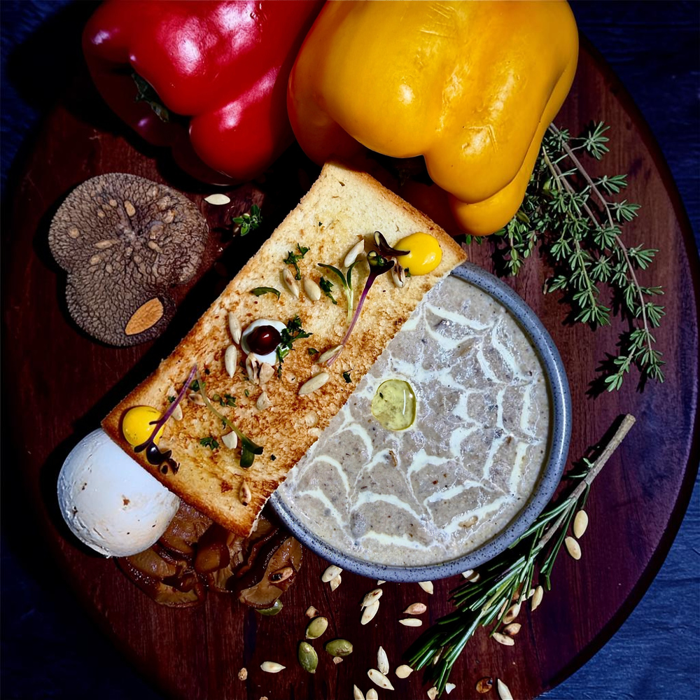 Rhukra Cake House Mushroom Cappuccino soup served with toasted biscotti, truffle oil, and fresh herbs on a wooden board